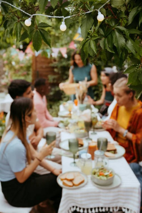 string light decoration on tree with friends celebrating during dinner party in back yard - garden decoration stock pictures, royalty-free photos & images
