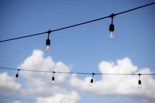 string lights against a blue sky with white puffy clouds - garden decoration stock pictures, royalty-free photos & images
