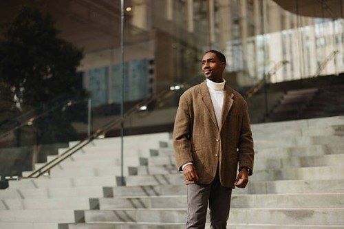 stylish man in brown jacket standing on modern urban steps outdoors - fashion stock pictures, royalty-free photos & images