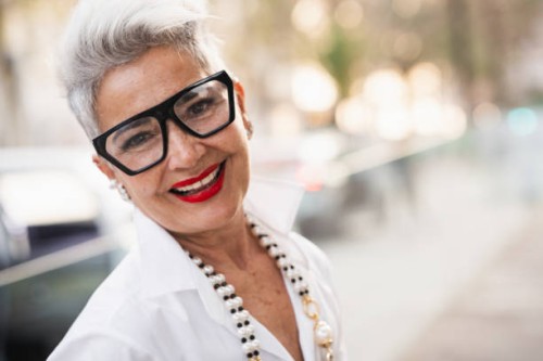 stylish senior businesswoman smiling outdoors with blurred city background - fashion stock pictures, royalty-free photos & images