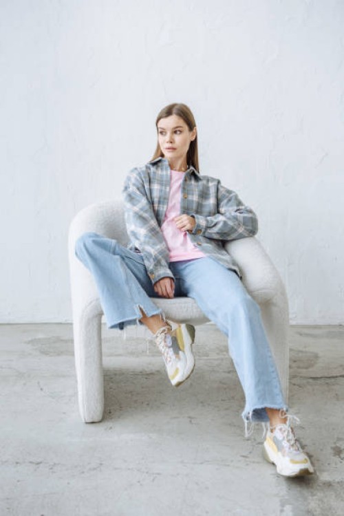 stylish young brunette woman posing sitting in a chair in casual clothes - fashion photos et images de collection