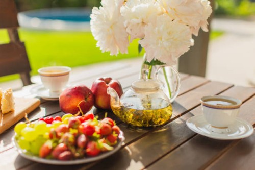 summer breakfast outside. green tea in teapot on wooden table. white peonies in vase. fruits on plate. fresh bakery. back yard of house. - garden decoration stock pictures, royalty-free photos & images
