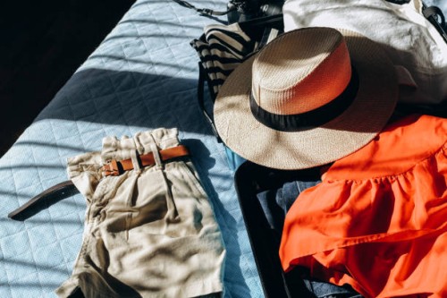 summer clothes in a suitcase luggage for travel, shadow overlay . french style t-shirt with stripes and straw summer hat. - fashion stock pictures, royalty-free photos & images
