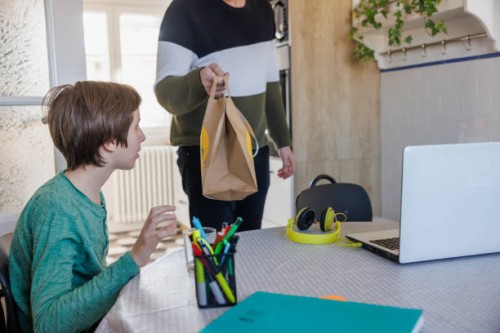 surprised boy looking at paper bag with food delivery in his father's hand - junk food stock pictures, royalty-free photos & images