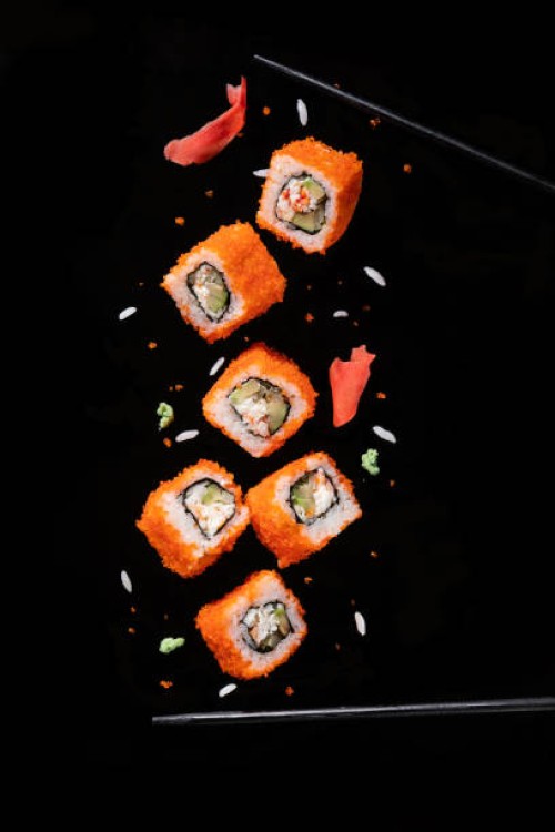 sushi pieces between chopsticks, flying separated on black background. - food stock pictures, royalty-free photos & images