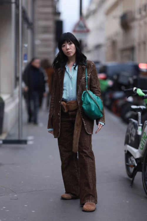 Susie Lau seen wearing green / white striped buttoned shirt, brown denim blazer jacket, matching brown denim / jeans wide leg pants, brown fluffy...