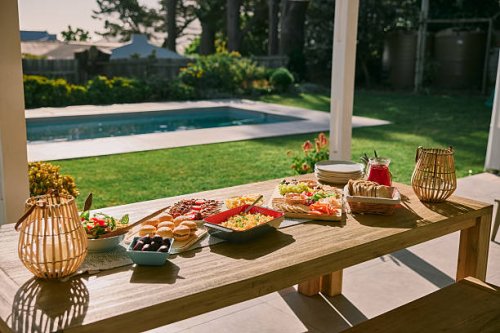 table, setting and food for lunch in backyard for social event, celebration and gathering by home. feast, patio and charcuterie board with burgers, salad and gourmet cuisine for outdoor dinner party - garden decoration stock