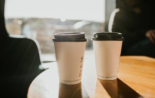 takeaway coffee cups on a wooden table casting long shadows - coffee stock pictures, royalty-free photos & images