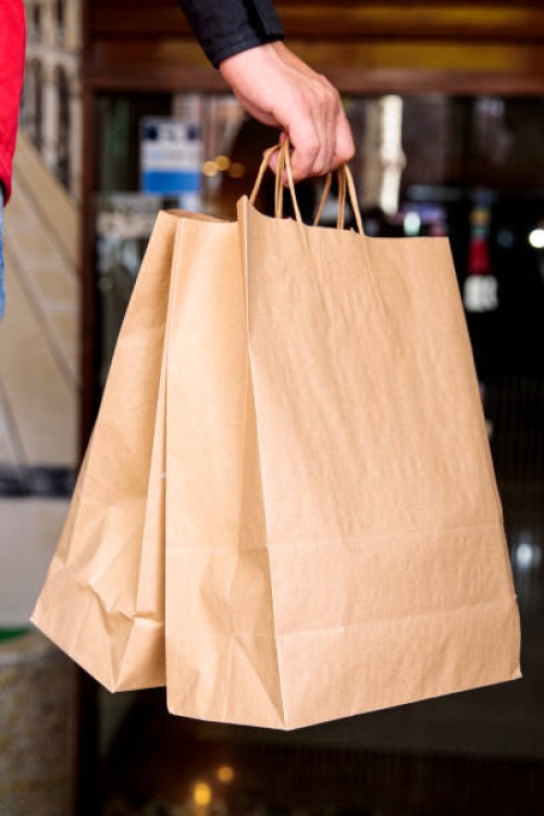 takeaway food delivery in deliveryman's hand, cardboard bags - junk food stock pictures, royalty-free photos & images