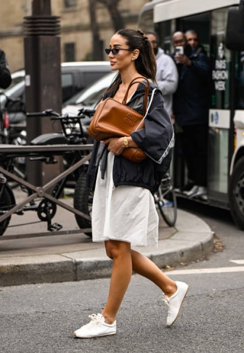 Tamara Kalinic is seen wearing a gray Miu Miu top, black Miu Miu jacket, white skirt, white sneakers and brown Miu Miu bag and black sunglasses...