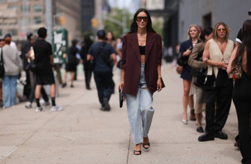 Tamara Kalinic is seen wearing large black shield-frame sunglasses with orange lenses and wide temples from Tom Ford, a long burgundy virgin wool...