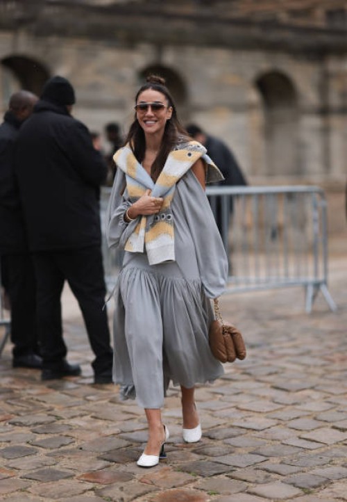 Tamara Kalinic was seen wearing white shoes, a grey dress, dark shades, a beige and grey scarf around her shoulders as well as a brown bag before the...