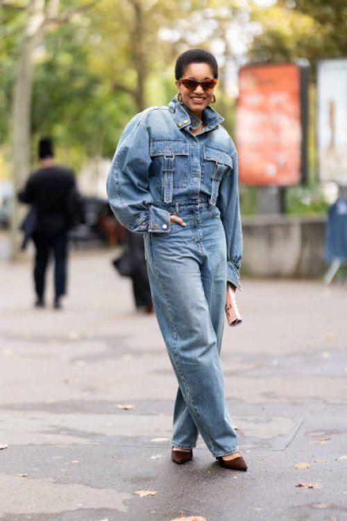 Tamu McPherson wears brown sunglasses, brown suede pumps and a denim cargo jumpsuit outside Zimmermann show during Womenswear Spring/Summer 2025 as...