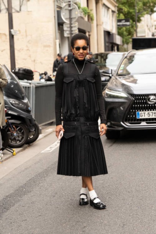 Tamu Mcpherson wears Maison Margiela shoes, Sacai dress and top and Prada sunglasses outside the Sacai show during Womenswear Spring/Summer 2025 as...