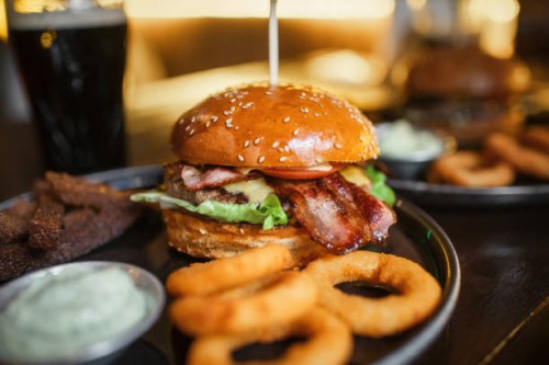 tasty beef burger with bacon, lettuce, cheese and tomato, onion rings, garlic sauce and a glass of beer - food stock pictures, royalty-free photos & images