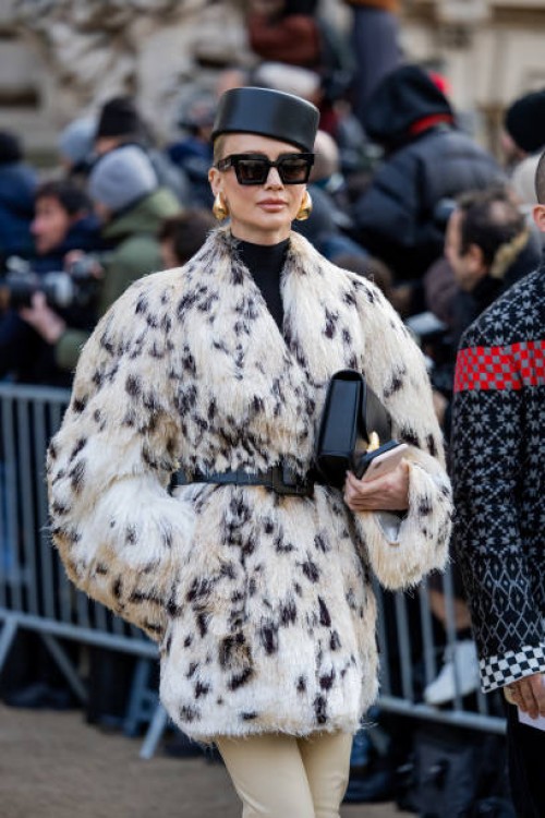 Tatiana Korsakova wears black hat, earrings, animal print white jacket with belt outside Schiaparelli during the Haute Couture Spring/Summer 2024 as...