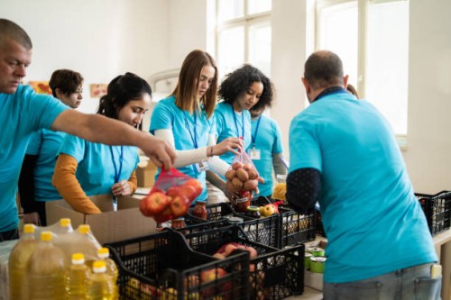 team of charity assistants packing food contributions - food stock pictures, royalty-free photos & images