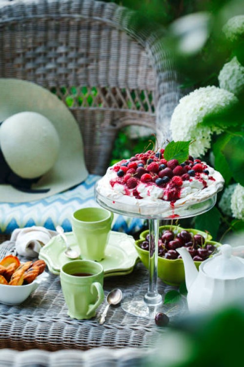 teatime in summer garden. meringue cake with berries or pavlova dessert - garden decoration stock pictures, royalty-free photos & images