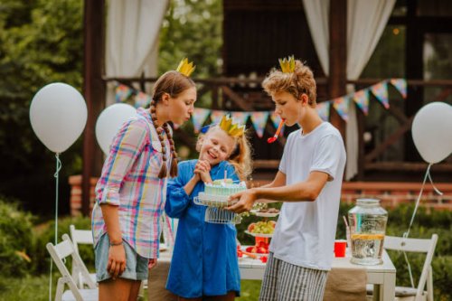 teen kids are posing near decorated birthday table. blowing the candle - garden decoration stock pictures, royalty-free photos & images