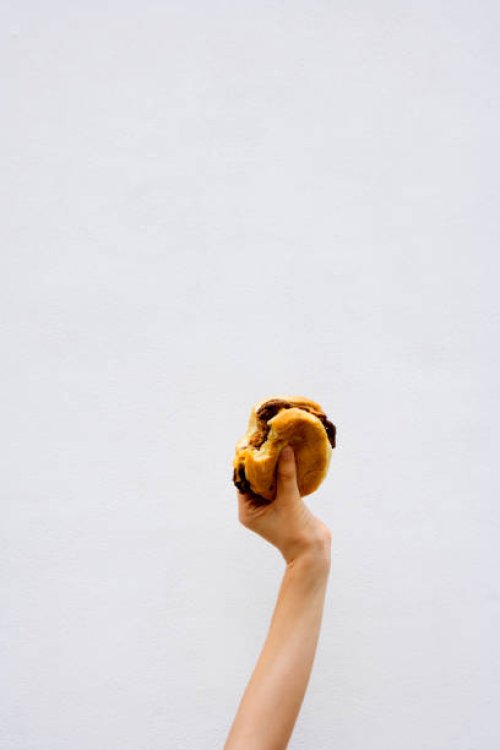 teenage boy (13-14) holding a bitten hamburger - junk food stock pictures, royalty-free photos & images