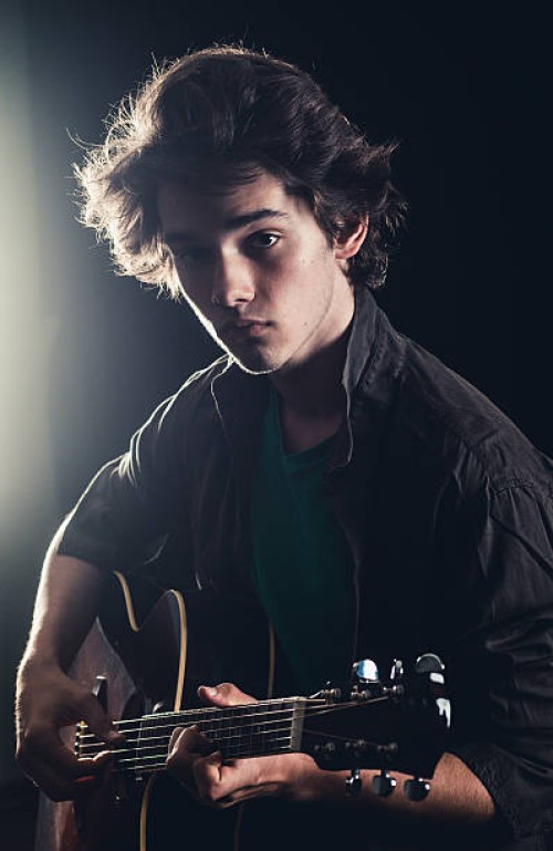 teenage boy playing acoustic guitar on stage - concert stock pictures, royalty-free photos & images