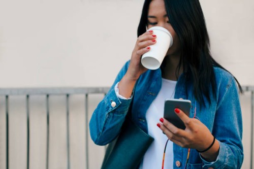 teenage girl drinking coffee while using mobile phone - junk food stock pictures, royalty-free photos & images