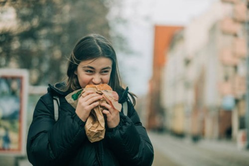 teenage girl eating burger on street - junk food stock pictures, royalty-free photos & images