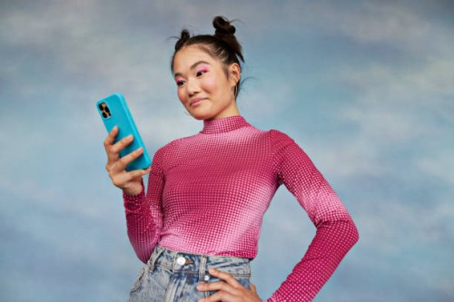 teenage girl using mobile phone while standing against colored background - fashion stock pictures, royalty-free photos & images