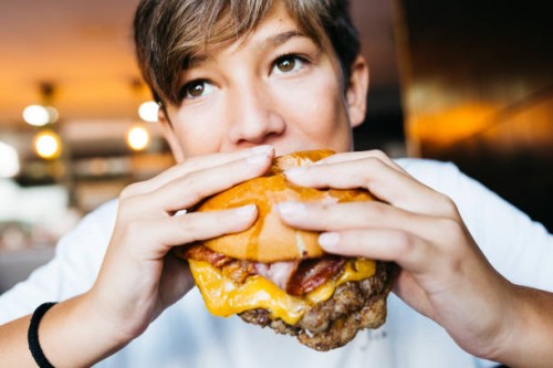 teenager eating a burger - food stockfoto's en -beelden