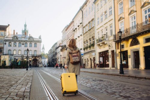 the beautiful cheerful woman with a suitcase walking on an ancient european street in the autumn - travel stock pictures, royalty-free photos & images