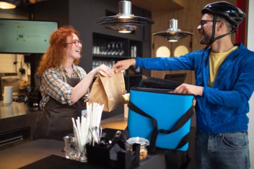 the delivery man picks up orders at the restaurant and packs them in a bag. - junk food stock pictures, royalty-free photos & images