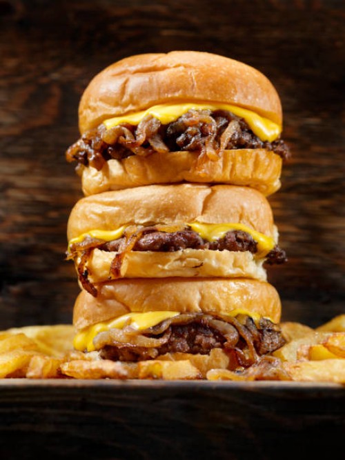 the famous fried onion smash burger with cheese and fries - junk food stock pictures, royalty-free photos & images