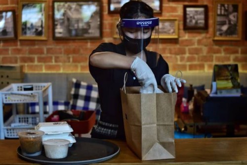 This photo taken on May 4, 2020 shows an employee from the high-end Thai restaurant At-Ta-Rote restaurant packing an order to be delivered by White...