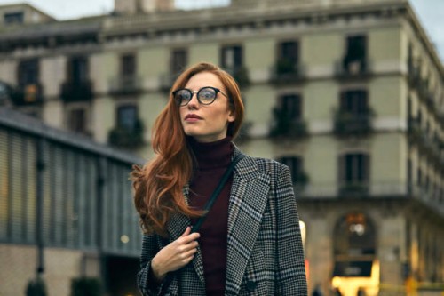 thoughtful woman wearing long coat walking in city - fashion stock pictures, royalty-free photos & images