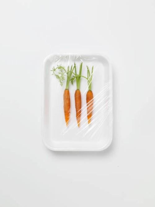 three baby carrots encased in plastic wrapping - food stock pictures, royalty-free photos & images