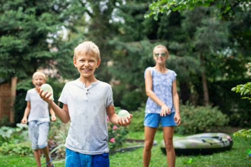 three children having fun throwing water bombs - garden decoration stock pictures, royalty-free photos & images