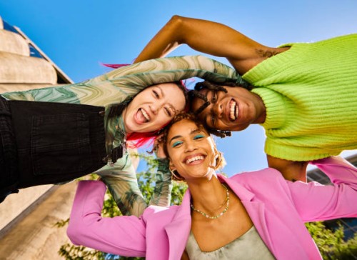 three gen z adults forming a circle with their arms and smiling outdoors in an urban environment. low angle shot. - fashion stock pictures, royalty-free photos & images