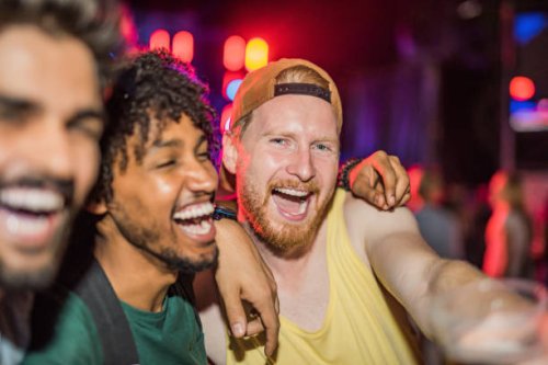 three happy young men partying at music festival at night. - concert stock pictures, royalty-free photos & images