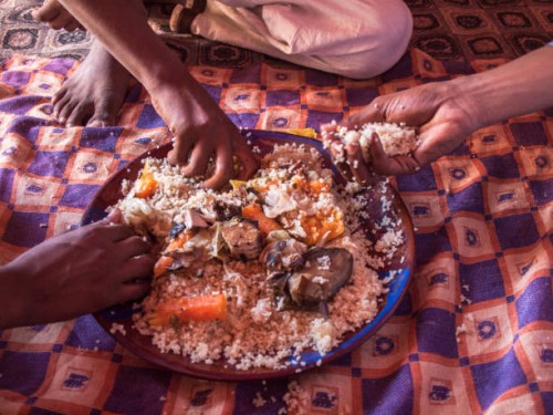 three men eat thieboudienne with their hands together from one plate - food stock pictures, royalty-free photos & images