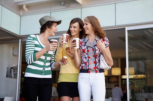 three teenage girls drinking take-out coffees and eating cakes - junk food stock pictures, royalty-free photos & images