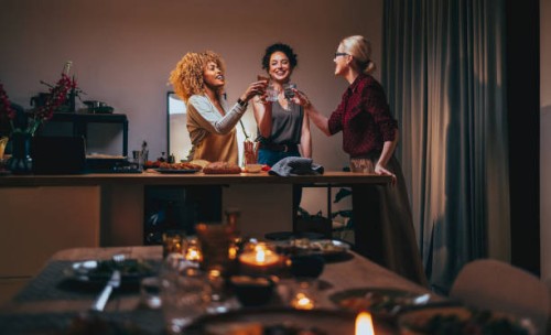three woman toasting with a glass of wine during a dinner preparation - food stock pictures, royalty-free photos & images