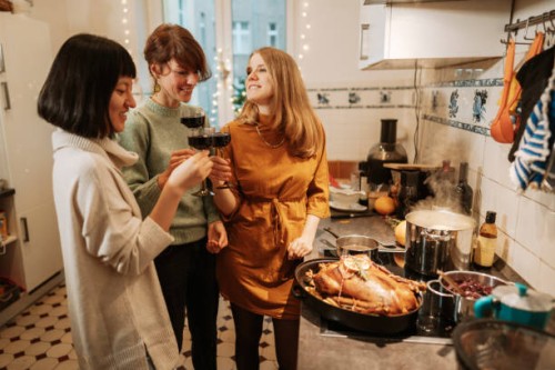 three women drinking wine while preparing christmas dinner at home - home decoration stock pictures, royalty-free photos & images
