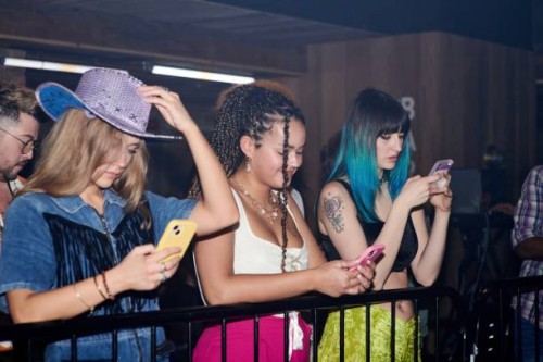 three women looking at their phones at a music event. - concert stock pictures, royalty-free photos & images