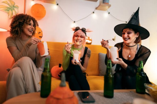 three young women in halloween costumes having fun together, talking and eating takeout food - junk food stock pictures, royalty-free photos & images
