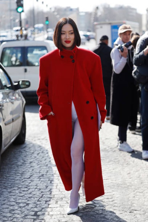Tiffany Hsu wears red long coat, white tights, white heels, outside Givenchy, during the Womenswear Fall/Winter 2025/2026 as part of Paris Fashion...