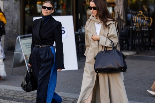 Tine Andrea wears high waisted navy, denim two tone jeans, black blazer, belt, bag & Annabel Rosendahl wears black bag, beige trench coat at Oslo...
