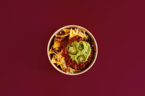 top view of a plate of nachos, traditional mexican food, on a plain maroon background. - junk food stock pictures, royalty-free photos & images