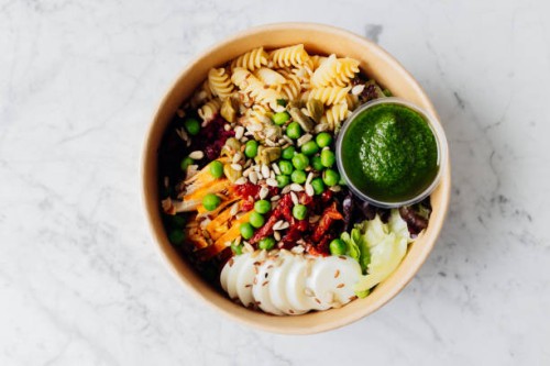 top view of healthy lunch bowl in reusable box. food bowl with chicken, pasta fusilli, mix greens, green peas, sun-dried tomatoes, beet, egg, sunflower seeds and pesto sauce - junk food stock pictures, royalty-free photos & i