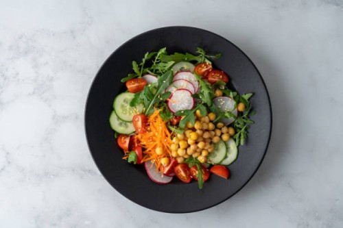 top view of vegetarian fresh salad with tomatoes, cucumbers, carrots, redishes, aragula, chickpeas - food stock pictures, royalty-free photos & images