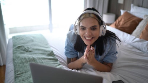 transgender woman watching something on laptop (or on a video call) at home - concert stock pictures, royalty-free photos & images